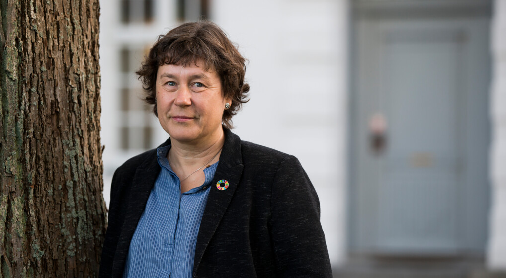 Marianne Christiansen i skjorte og blazer står op af træ