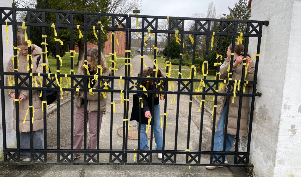 Unge mennesker binder gule bånd på en låge