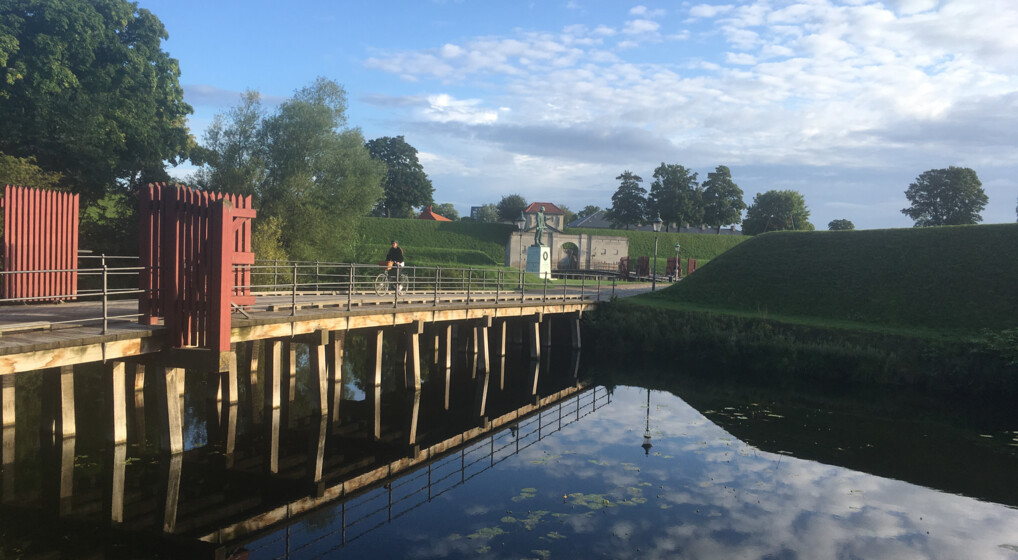 Cyklist på bro over vandgrav ved kastellet