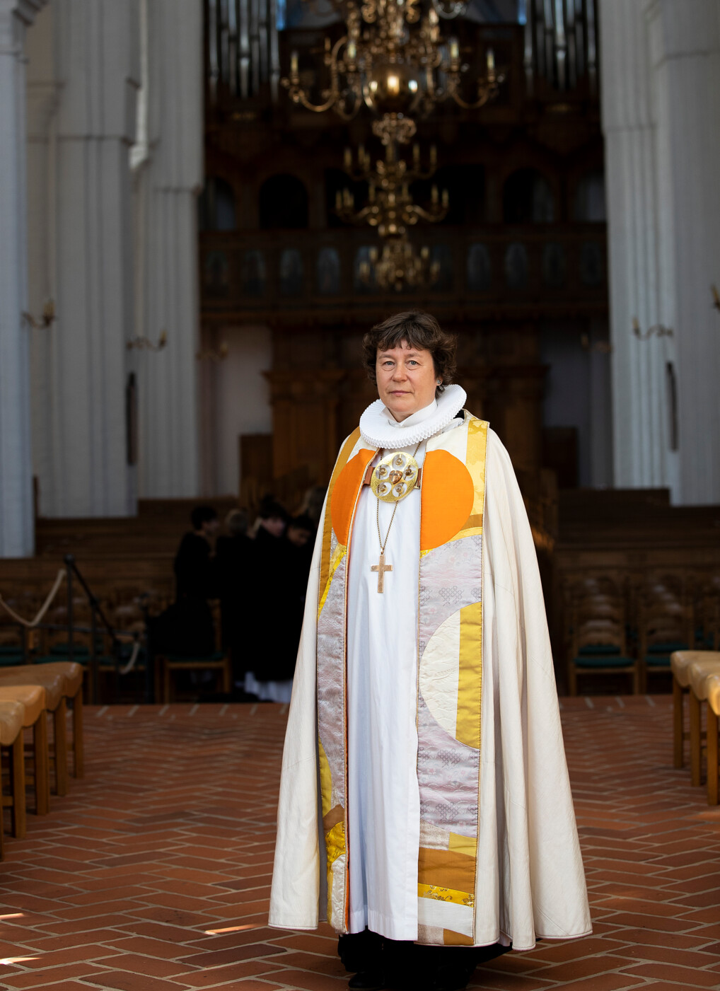 Fuldkropsbillede af Biskop Marianne Christiansen i bispekåbe og præstekrave